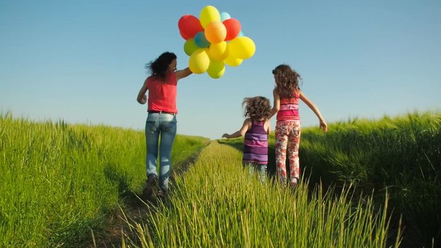 Happy family with balloons. Mom with children in a field with balloons.