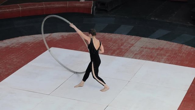 Skilled professional circus artist training with a big cyr wheel on stage