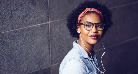 Stylish young woman listening to music on earphones