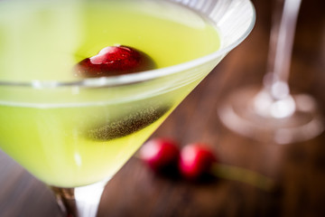 Appletini Cocktail with cherry on wooden surface.