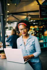Fototapeta premium Smiling young African woman working in a cafe