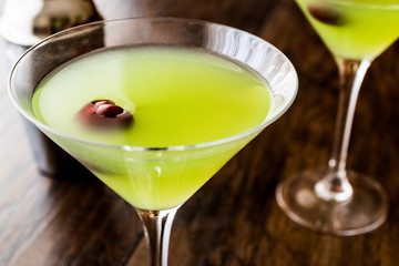 Appletini Cocktail with cherry on wooden surface.