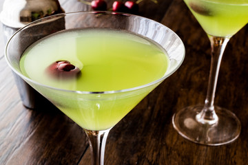 Appletini Cocktail with cherry on wooden surface.