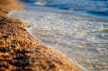 pebbles on the beach pebbles on the sea shore and waves of water illuminated by the rays of the sun