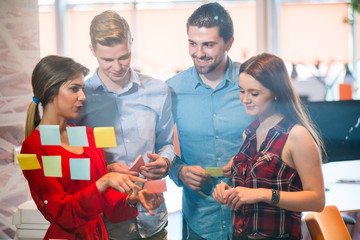 business, startup, planning, management and people concept - happy creative team with stickers on office glass board talking at office