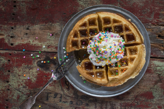 Plate Of Waffles With Whip Cream And Sprinkles On Rustic Table