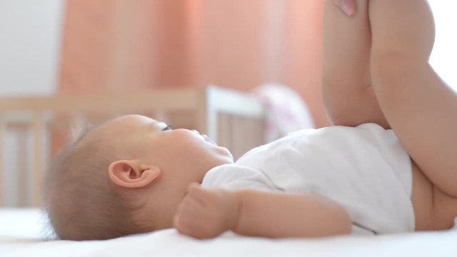 Baby Nursing on Bed with Mother Changing Diapers