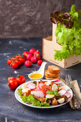 Healthy food - vegetables and salmon salad on a dark background. Selective focus. Copy space