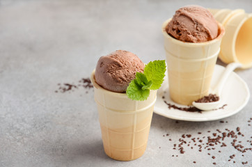 Chocolate ice cream in waffle cone on grey concrete background, selective focus, copy space