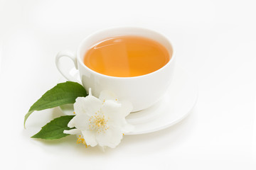 Jasmine flowers and cup of green tea on white. Side view and concept.