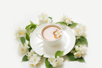 Jasmine flowers around cup of green tea on white background. Top view and concept.