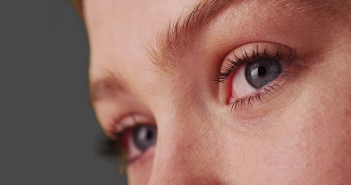 low angle view of beautiful woman with blue eyes on grey background.