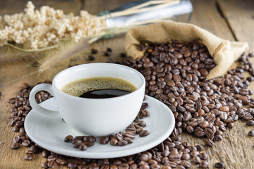 Coffee cup with coffee beans on wood table