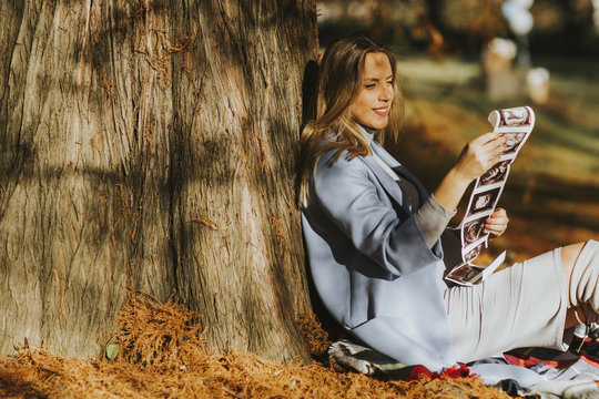 Young pregnant woman looking fetus ultrasound images in the park