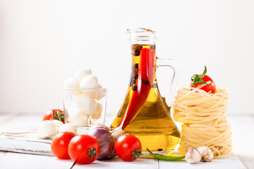 Olive oil with pepper in a bottle, paste, cheese and tomatoes on a light background. Selective focus. Copy space