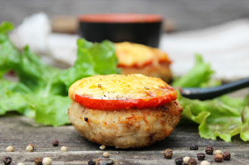 Grilled meatballs with tomato and cheese.