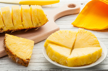slices of a pineapple on white wooden background