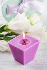 Obraz na płótnie Canvas Arrangement of white eustoma flowers and purple lit candle