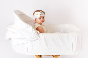 Beautiful baby girl in the crib on a white background