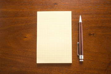 Pen and blank paper on a wooden background
