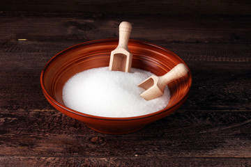 scoop with white sand and lump sugar on brown wooden background