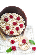 Oatmeal flakes and raspberries on white background.