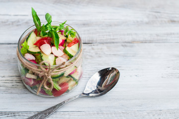 Sliced vegetables in a glass jar on a light background, vegetable salad. The concept of healthy eating.