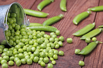 Fresh green peas in bucket on brown wooden table