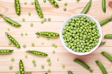 Fresh green peas in bowl on wooden table
