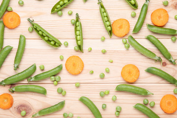 Green peas and carrots sliced on wooden table