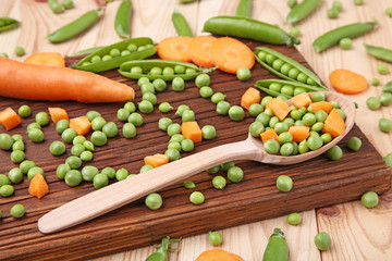 Green peas and carrots sliced on wooden table