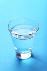 Glass with water on blue background