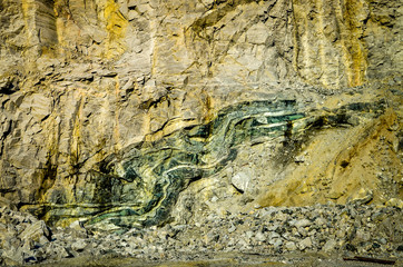 green folded rock formation inside mountain wall