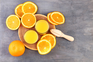 Glass of orange juice and juicer on grey wooden table