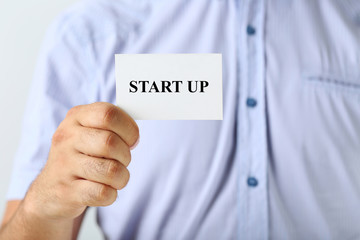 Male hand holding a business card with word Start up