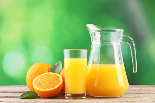 Glass jug with orange juice on wooden table