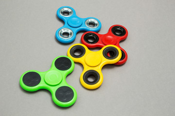Multi Colored fidget finger spinner stress on grey background.