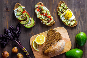 Sandwiches for breakfast with avocado, fried eggs and lemon juice on wooden table top view
