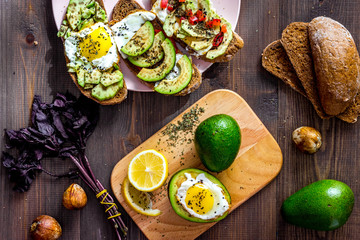 Sandwiches for breakfast with avocado, fried eggs and lemon juice on wooden table top view