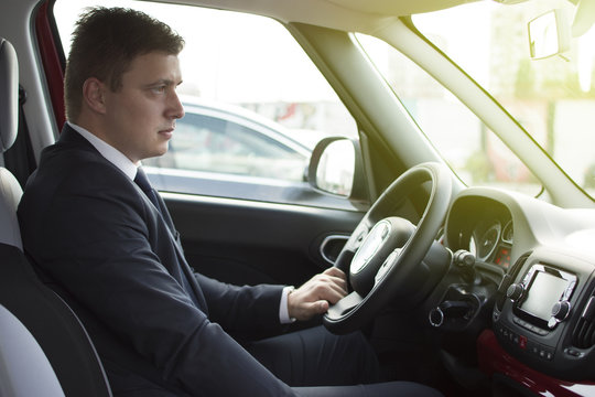 Businessman sitting in his car in a highway jam. Looking in the distance while in traffic. Suit and tie businessman sitting in his automobile.