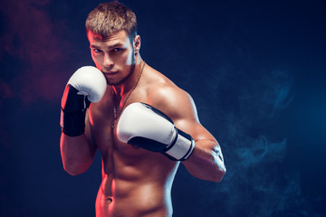 Aggressive shirtless boxer on dark smoke background. - obrazy, fototapety, plakaty