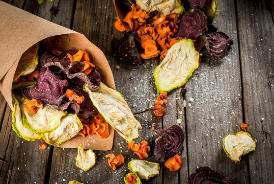 Organic diet food. The vegan diet. Dried vegetables. Homemade chips from beets, carrots and zucchini. On old wooden rustic table, with fresh vegetables. Copy space