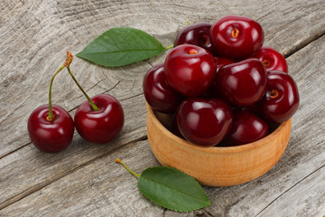 cherries in bowl on old wooden background.