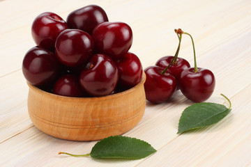 cherries in bowl on white wooden background. Top view