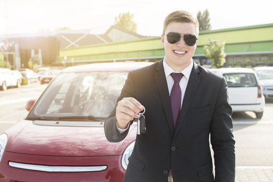 Close-up of a young business man holding car keys. Brand new car. Man smiling while holding car keys.
