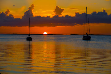 sunset over ocean bay with anchored boats