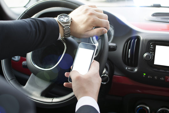 Close-up of a man's hand holding a smartphone. Businessman texting while sitting in a car. Holding a steering wheel and using a mobile phone.
