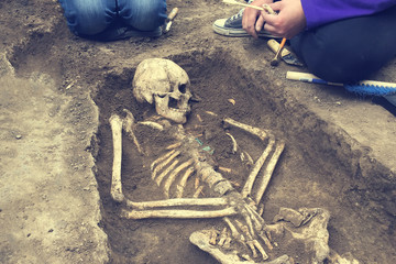Archaeological excavations.  archaeologist with tools conducts research on human burial, skeleton,...