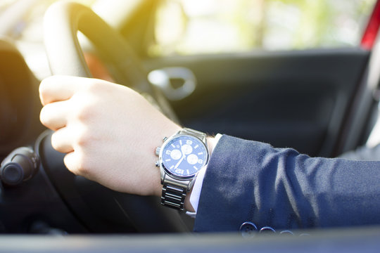 Close-up of a young businessman hand on the steering wheel. Lens flare in the background. Businessman driving a car concept.