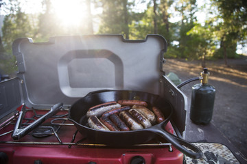 Cooking brats and hot dogs in a cast iron skillet by the lake 